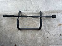 Top-down view of black metal doorway pull-up bar with foam grips showing entire bar and pads.