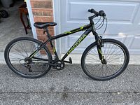 Side view of DIADORA black hybrid bike with visible branding, flat rear tire, and knobby tires on asphalt surface.