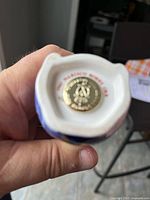 Bottom of bone china figurine showing Royal Crown Derby mark and gold sticker