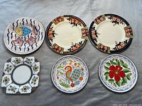 Top view of six decorative plates showing fish design, Aynsley square plate, two Windsor Derby round plates, and two smaller floral plates from Greece.