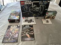 Full lot arranged on a bed showing all collectible items including sealed LEGO Star Wars 75347 box with visible minor box damage, empty LEGO Star Wars boxes for sets 75347 and 75344, their manuals, two Star Wars books.