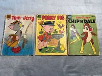 Front view of three comic books showing cover art featuring Tom and Jerry, Porky Pig, and Chip 'N' Dale