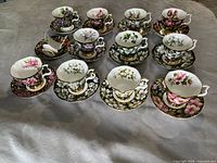 Complete set of 12 teacups and 12 saucers showing various provincial floral designs with gold trim.