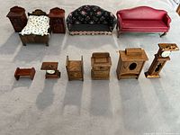 All 11 pieces of the vintage wooden dollhouse furniture including bed, sofas, nightstands, cabinets, and clocks arranged on neutral floor.