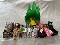 Photo showing all dolls arranged with Yellow Brick Road stand in background, includes original tags and packaging for Lion doll.