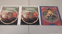 Three Selectavision movie discs with artwork for Excalibur parts 1 and 2, and Dragonslayer arranged side by side.