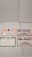 Four antique stock certificates displayed on a white surface, including two Missouri, Kansas and Texas Railway Company certificates, one National Protective Companies certificate, and one North American Pulp and Paper Companies certificate.