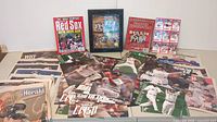 Overview of collection laid out showing multiple newspapers, magazines, cards, and plaques commemorating Boston Red Sox 2004 and 2007 championships.