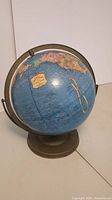Full globe showing blue ocean and parts of continents with metal stand