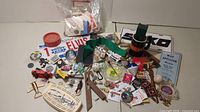 Wide view of assorted small collectibles and household items including toy tractor, cribbage board, license plates, pins, and buttons.