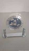 Front view of the clear acrylic desk clock showing the world map face and Arabic numerals.