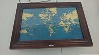Front view of the Howard Miller world time clock displaying a world map with time zones, framed in wood.