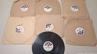 Seven 78 rpm records with paper sleeves and 'Kicks' labels, one record out of sleeve showing label and logo
