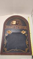 Full view of 23-inch tall arched vintage kitchen chalkboard sign with "Today's Coffee 5¢" text, decorative painted coffee cup and pot at the top, and two ceramic teapot accents affixed on the board.