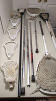 Various lacrosse heads and shafts arranged on table, showing condition and quantity of heads and shafts