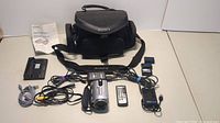 All items together showing camera, batteries, charger, cables, remote, and bag