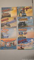 Fold-out souvenir postcard folders from Albany NY, New York City NY, Columbus OH, Lexington KY, Niagara Falls, Kentucky, and Vicksburg MS are shown laid out flat. Each folder cover features colorful images and city/state names.
