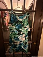 Full view of sleeveless floral sheath dress hanging on hanger