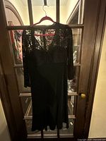 Full view of black lace cocktail dress on hanger