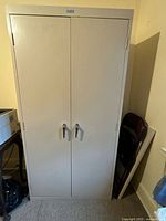 Front view of closed beige metal cabinet with two metal handles