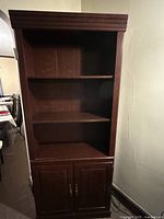 Front view of tall dark brown bookshelf showing shelves and cabinet doors