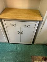 Front view of cabinet showing drawer, doors, chrome handles, and size context