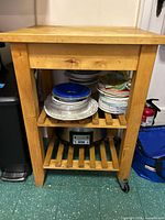 Front view of wood cart showing top, two slatted shelves, and casters