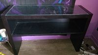 Photo of black console table showing front and side angle with glass top and one open shelf