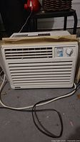 Front view of white Everstar air conditioner unit showing horizontal vent slats and power cord on floor.