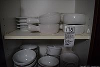 Stacks of handled soup bowls, fluted ramekins and assorted bowls on cabinet shelves