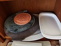 Round marble board, terracotta tile, white dish and platter inside cabinet