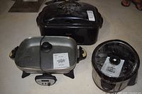 Three countertop cooking appliances with manuals: Bravetti roaster, Rival skillet, Rival crock-pot