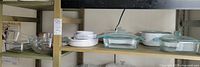Shelved assortment showing clear glass casseroles, white ceramic dishes and mixing bowls