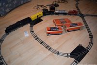 Overall view of assembled track layout with locomotive, rolling stock, transformer and orange Lionel boxes