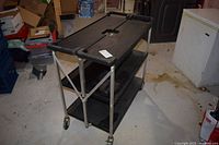 Full view of folding trolley showing three shelves and casters