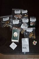 Overall lot showing sealed bags of findings, boxed charm, certificate and small floral accent