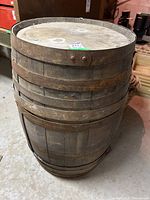 Front and side views of a wooden bourbon whiskey barrel showing rusty metal hoops and weathered wood.