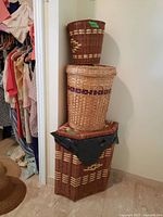 Photo showing three stacked woven baskets including the largest rectangular hamper on the bottom, medium round basket in middle, and smallest basket on top.
