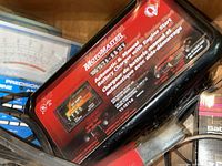 Close-up of Motomaster battery charger showing model, voltages supported, and automatic/manual operation.