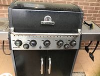 Front view of Broil King Baron gas BBQ grill showing six control knobs and dual front cabinet doors.