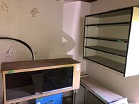 Photo showing the smaller cabinet with black glass door and the countertop cabinet beneath it, plus part of the large wall-mounted cabinet.