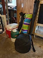 View of all items including red cooler, green jug, three camp chairs in bags, and black air mattress bag.