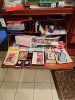 Image of a collection of cards, ribbons, wrap, tin box, fabric bags, and candles on a wooden desk