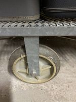 Close-up of one of the metal cart's large rubber wheels and metal bracket.