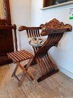 Photo showing the wood carved chair with lion-head armrests and small wood side table beside it.