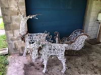 Photo showing the two wireframe reindeer and the sleigh together, outdoors on concrete surface against blue wall.