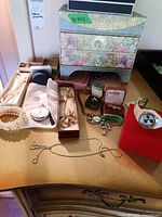 Full view of assorted jewelry including pearl necklaces and bracelet, pocket watch, costume necklaces, Continental earrings in green box, ring in Sears box, hard paper decorative jewelry box with drawers