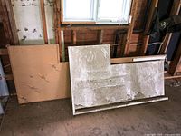 Two countertops leaning against wall under window showing size and condition, with dirt and dust visible.