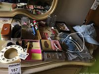 Overview of dresser top with all items spread out including cards, cufflinks, pins, clips, phone cord, and corkscrew.