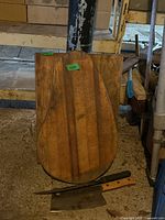 Two wooden cutting boards with one in front showing wear and the back larger with similar finish, placed against a post in garage setting with some tools visible.